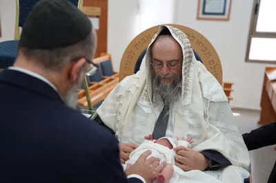 צילום ברית - הרב מחזיק את התינוק